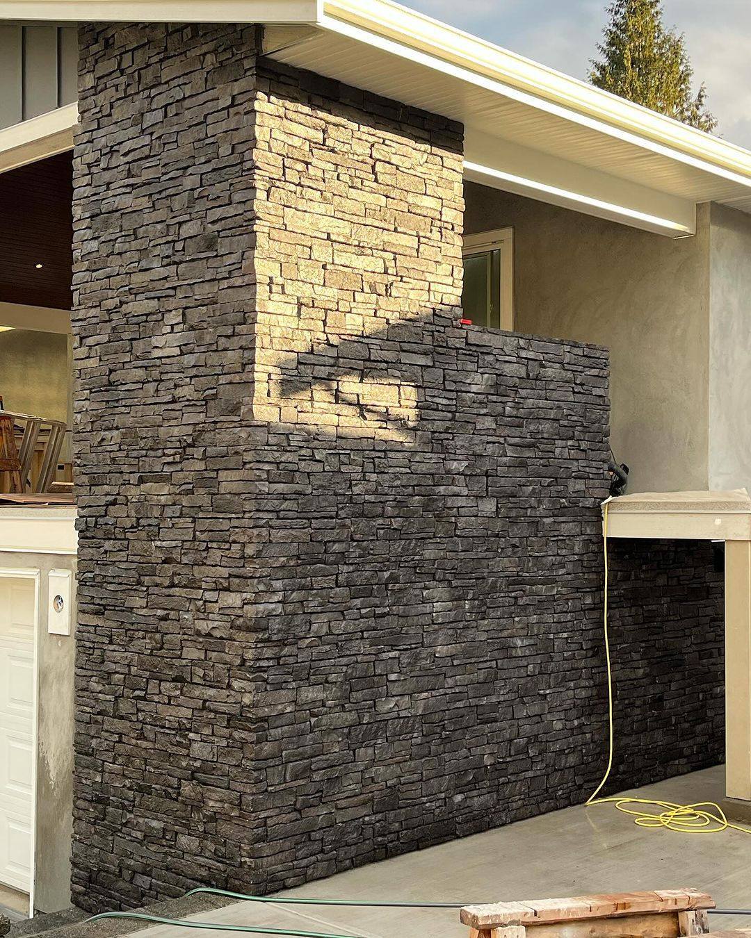Exterior corner of a home with dark stacked stone veneer