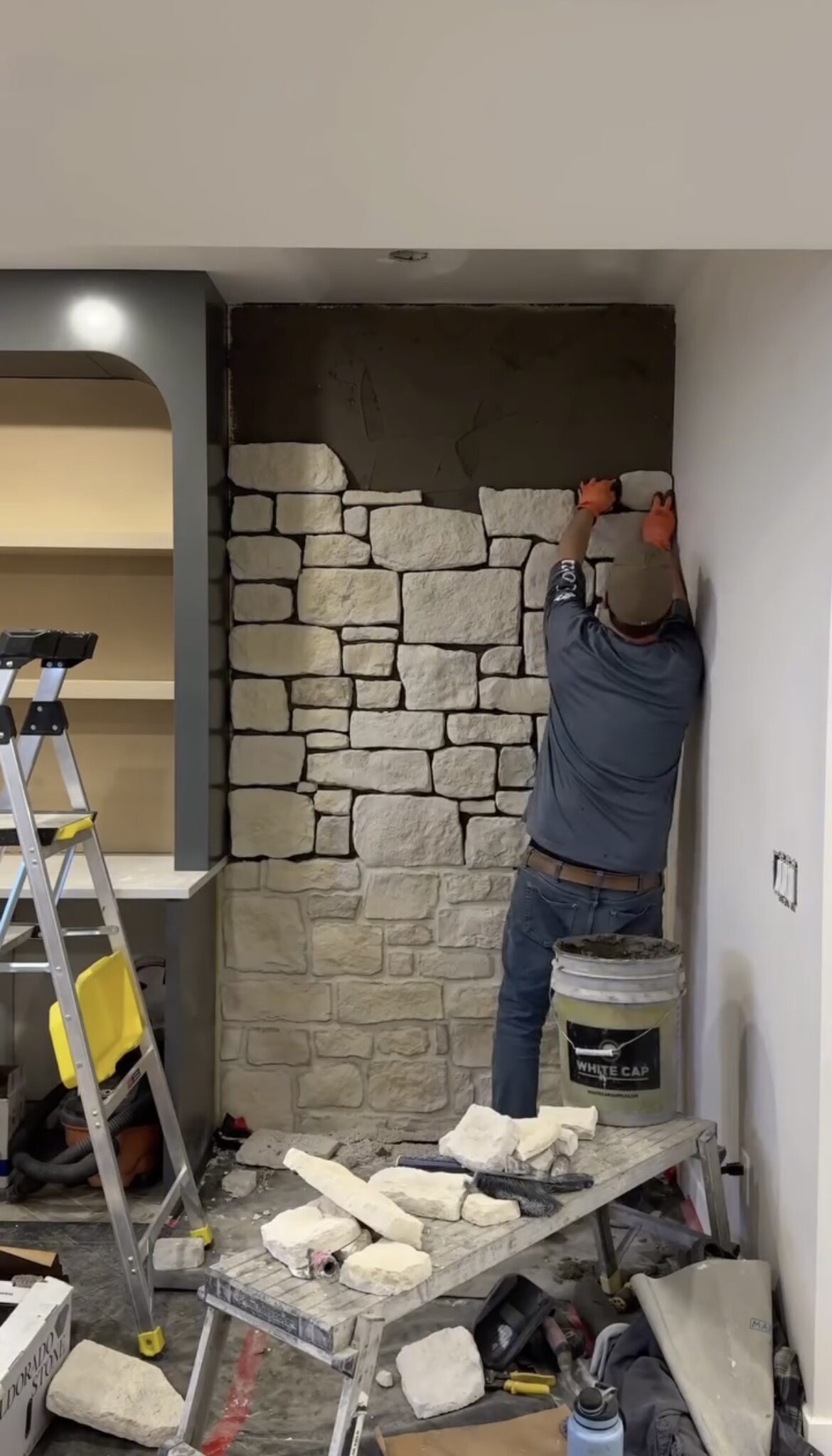 Mason installing stone veneer on an interior wall