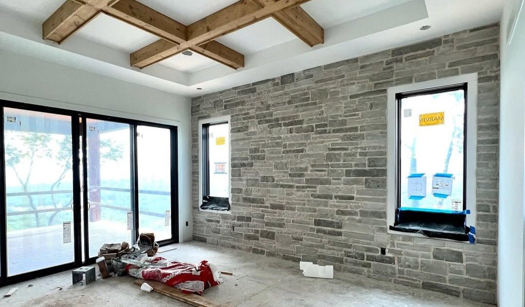 Living room under construction with a grey stone feature wall