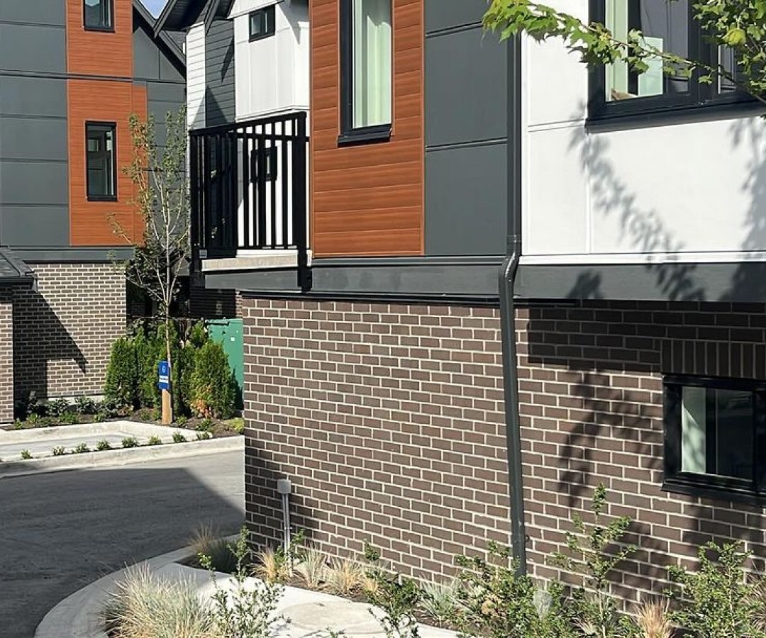 Modern townhouse with dark brown brick veneer and mixed exterior cladding.