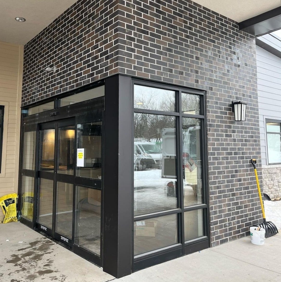 Dark brick wraps the exterior corner around the storefront entrance.